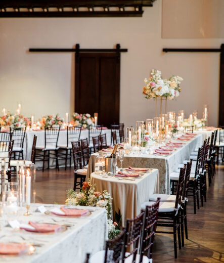 delicate gold details, lush floral arrangements in hues of white and pink with verdant greenery, the soft glow of candles
