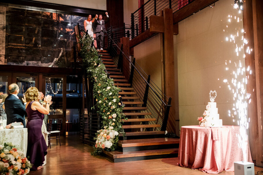 bride and groom entering the reception down the stair cake as cold sparks go off