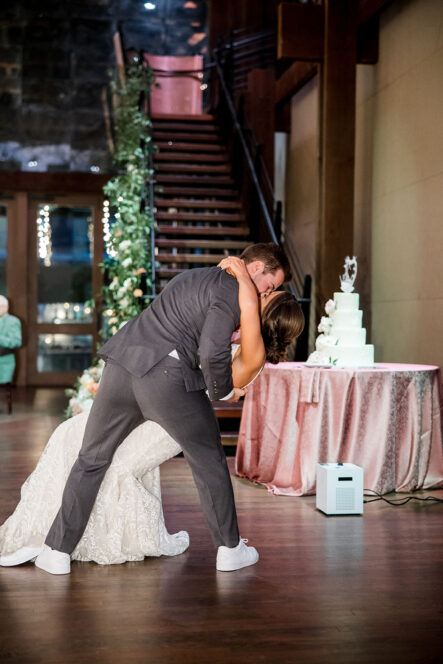 bride and groom first dance in front of the cake and staircase