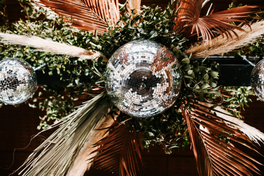 Disco ball installation with greenery and dried palms