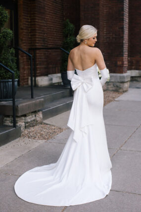 Bride wearing strapless wedding gown with bow and gloves